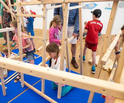 Kinder spielen in einem Holzgerüst.